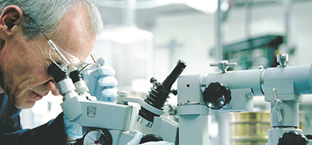 Man looking into a microscope in a lab