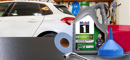 Mobil 1 ESP 5W-30 z wiadrem lejkowym i rolką chusteczek przed samochodem